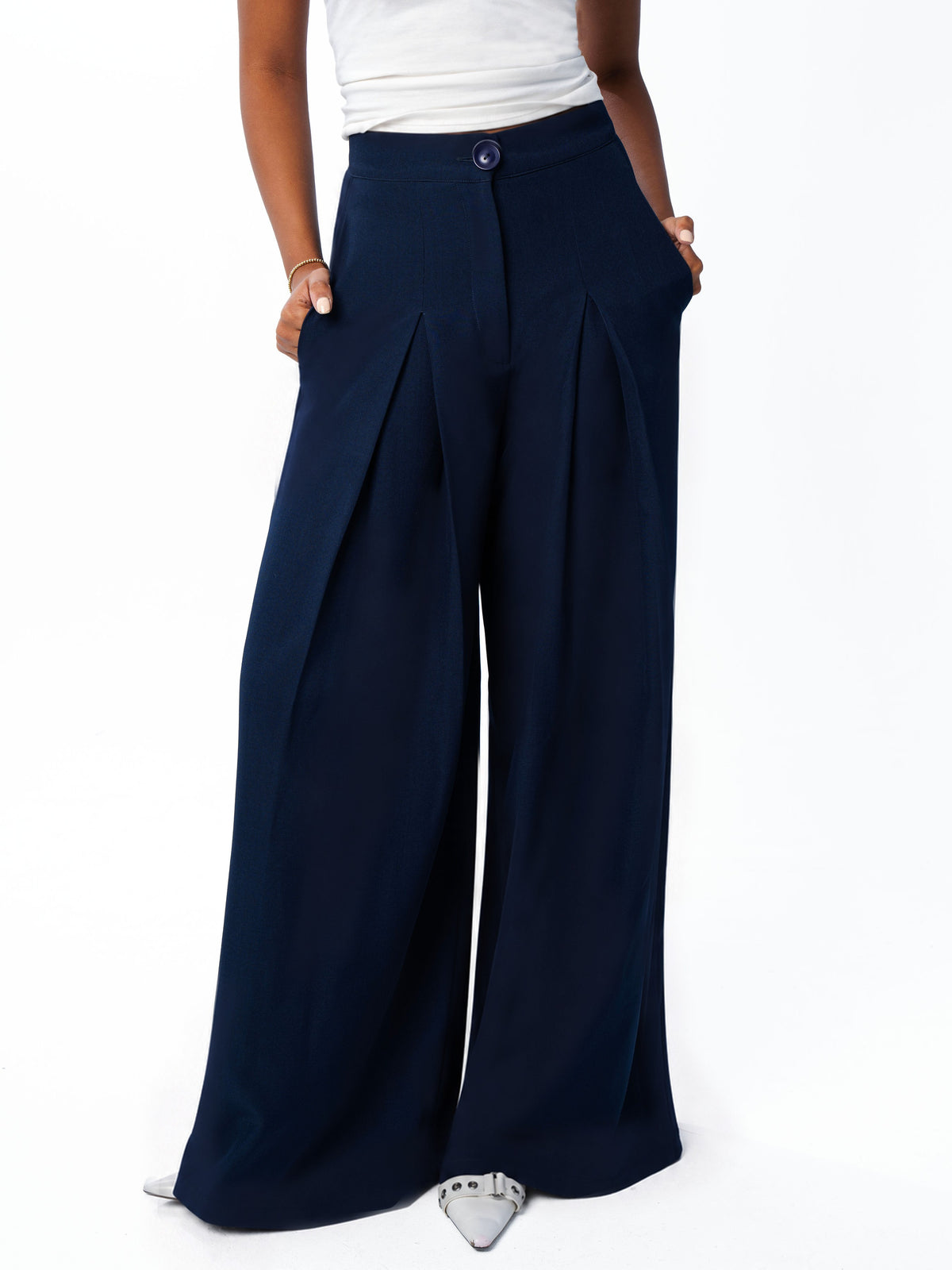 Close view of the navy trouser waistband, button and inverted pleats